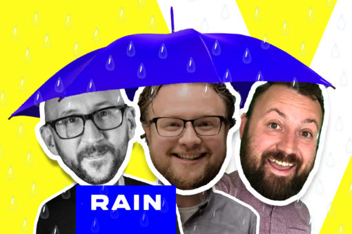 RAIN agency's Will Hall and Jason Herndon with VUX World host, Kane Simms, standing under an umbrella in the rain