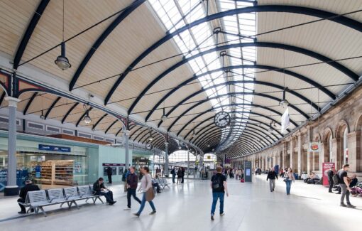 Image of Newcastle station interior. It looks like it could also be a shopping mall. There's a lot of people, ATMs, fast food, shops, and seating areas 